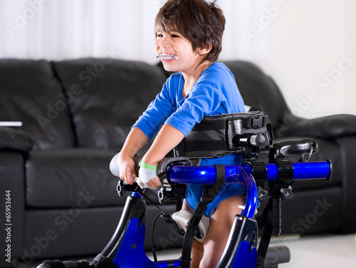 Disabled biracial boy in medical walker. Living room setting.