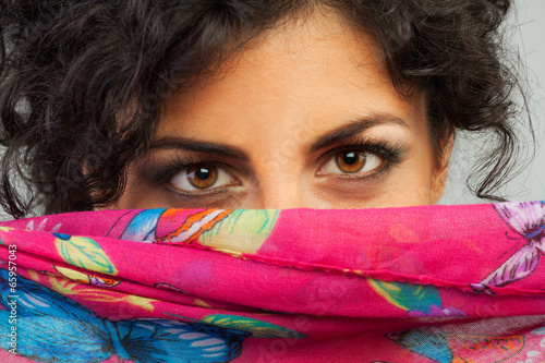 Beautiful woman with brown eyes hiding behind a scarf photo