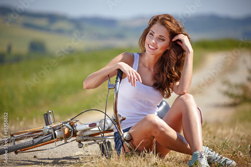 beautiful smiling girl sitting next to bike, summer time