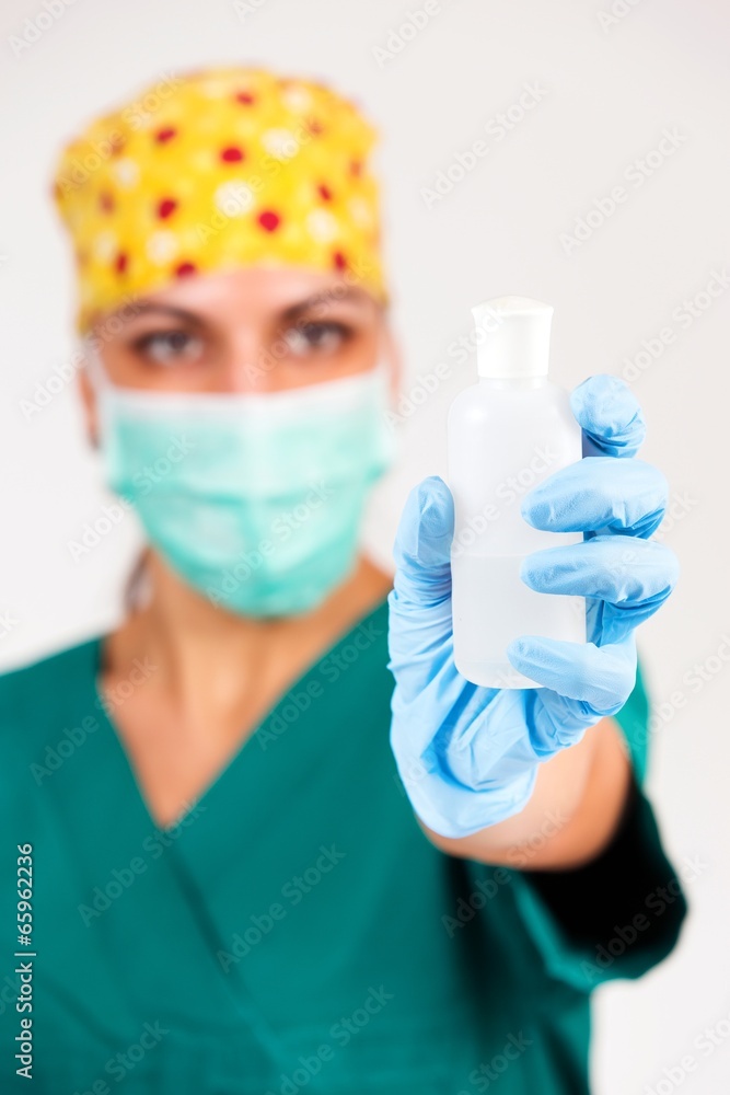 Female surgeon presenting new medicine in white bottle Female surgeon presenting new medicine in white bottle