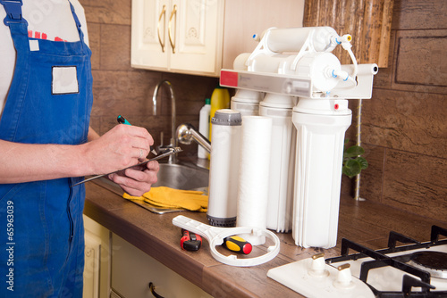 Young handsome plumber plumbing repairs. Replacement water filte