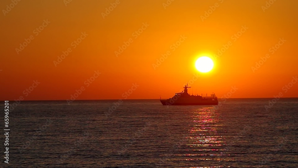 Cargo ship sailing away against colorful sunset Cargo ship sailing away against colorful sunset