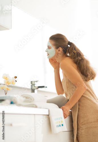 Young woman wearing facial cosmetic mask in bathroom