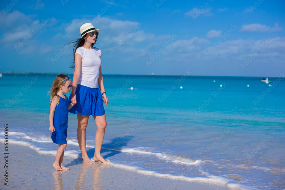 Mother and her little daughter walking at tropical beach