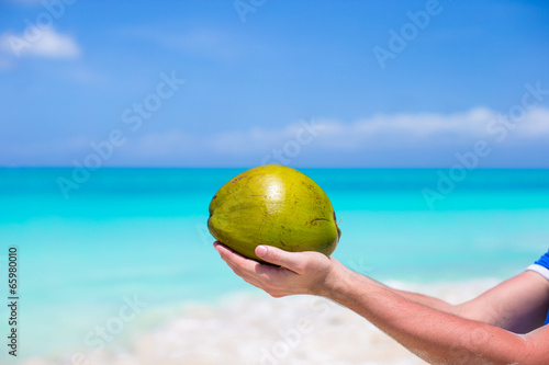 Closeup of coconut in hands against the turquoise sea © travnikovstudio