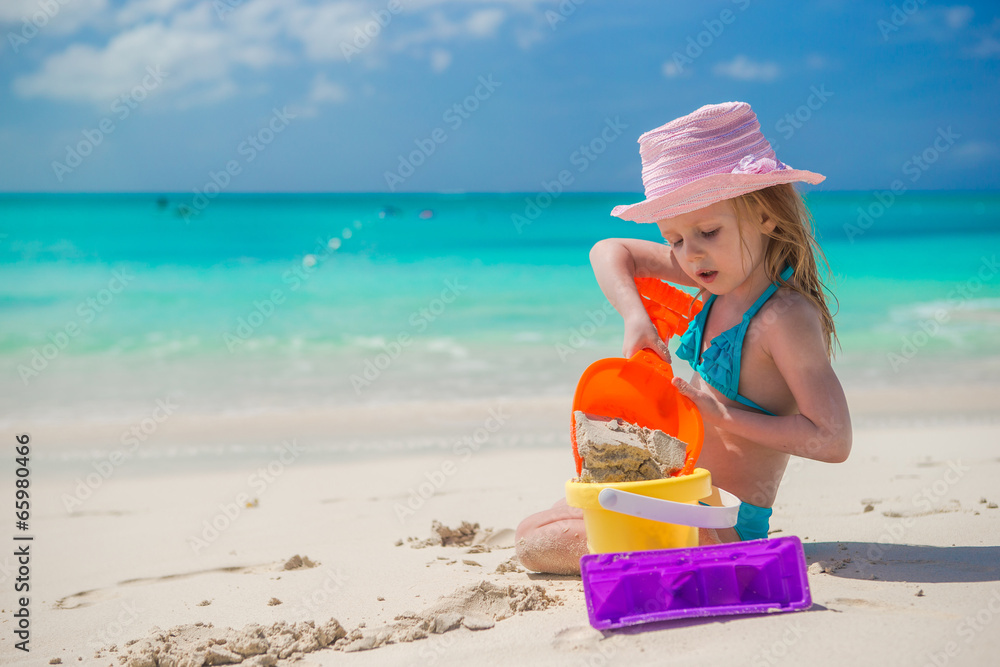 Adorable little girl playing with sand on a perfect tropical Adorable little girl playing with sand on a perfect tropical