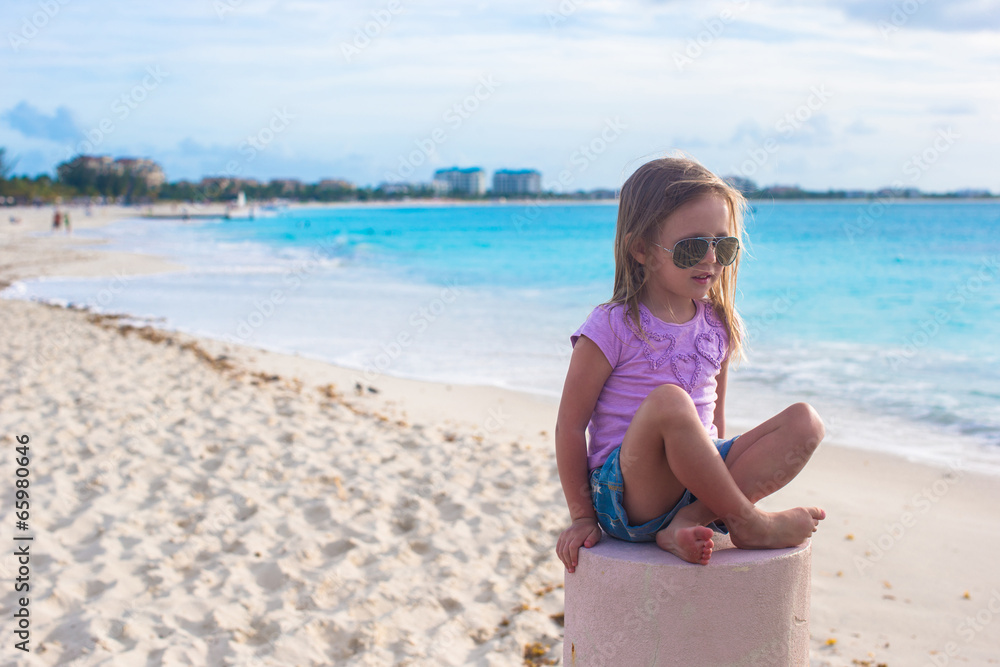 Adorable little girl sitting in a lotus position on an exotic Adorable little girl sitting in a lotus position on an exotic