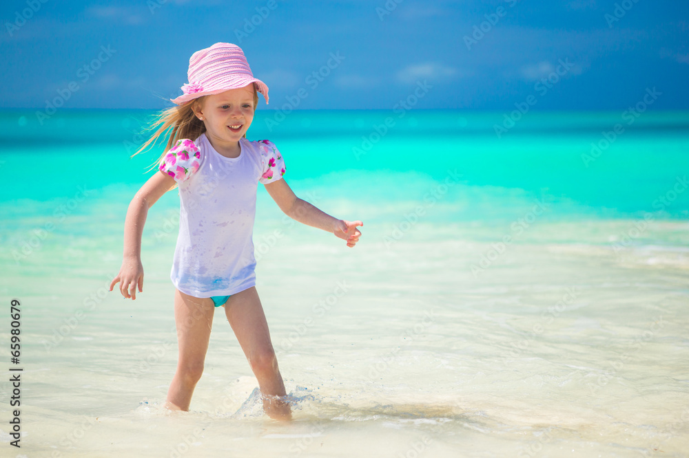 Adorable toddler girl playing in shallow water at exotic beach Adorable toddler girl playing in shallow water at exotic beach