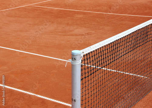 Tennis net at empty red gravel court photo