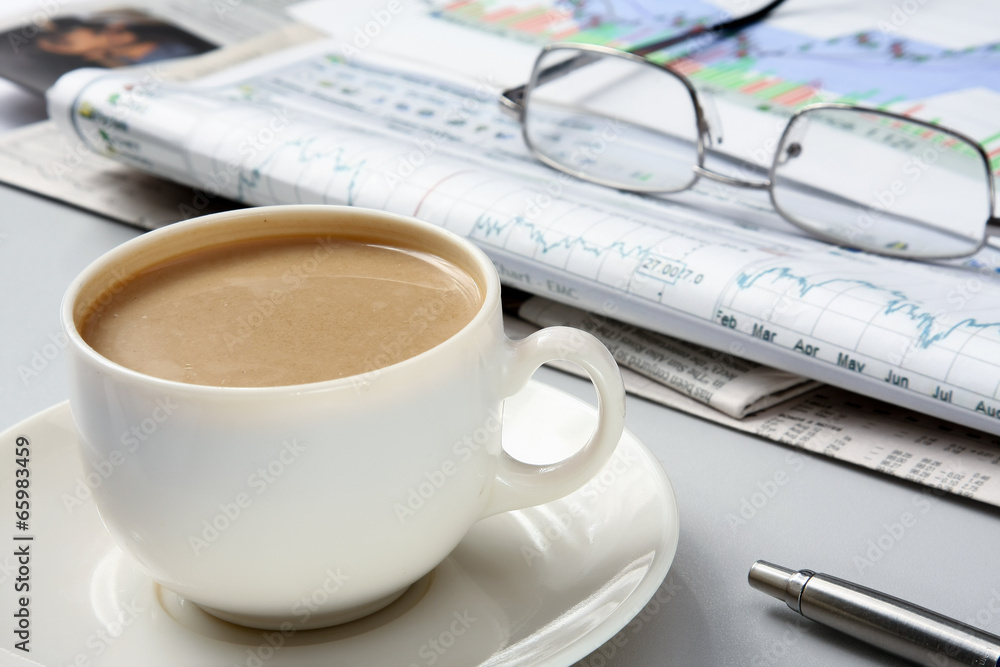 cup of coffee near the laptop and newspapers cup of coffee near the laptop and newspapers