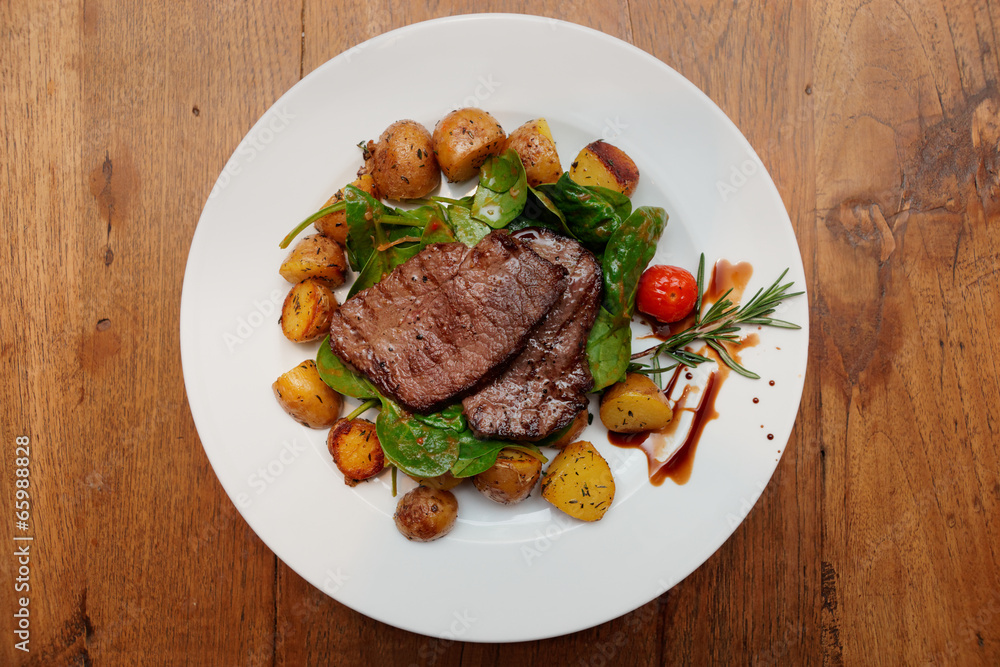Steak with fried potatoes on wooden table Steak with fried potatoes on wooden table