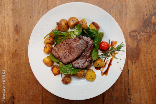 Steak with fried potatoes on wooden table