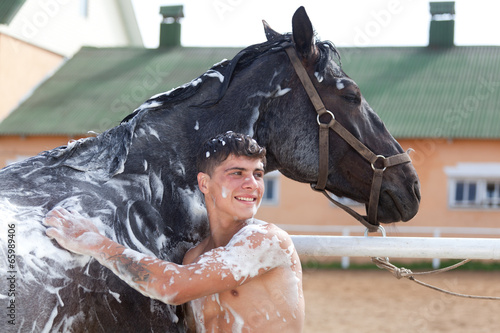  young sexy man washes a horse photo