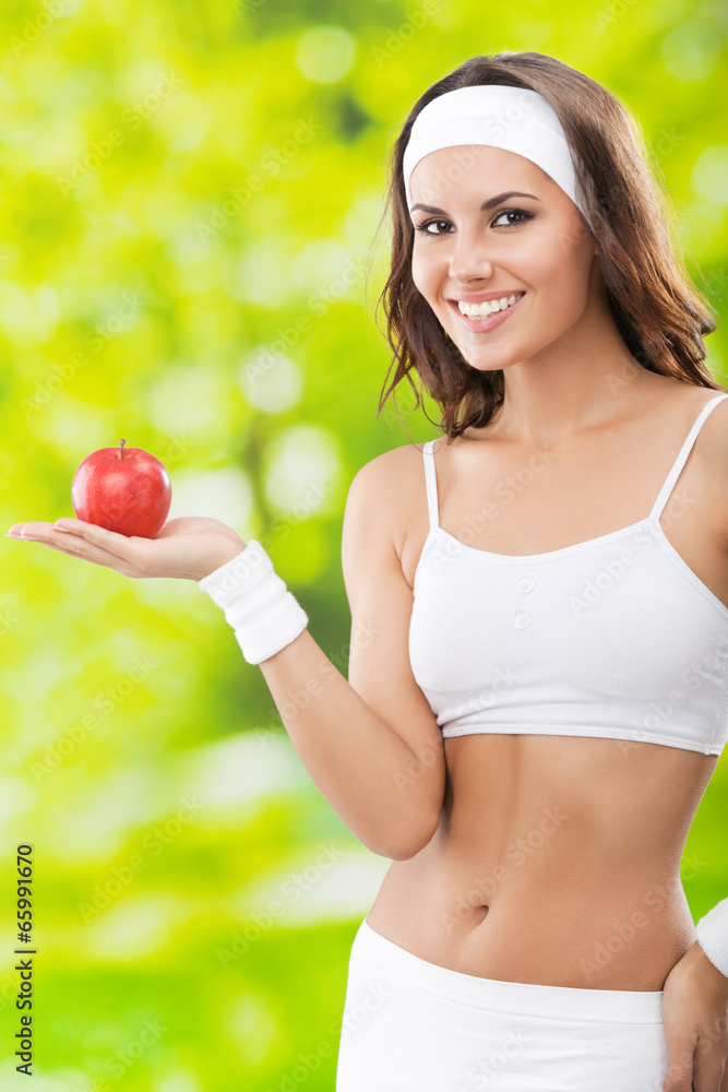 Woman in fitness wear with apple, outdoors Woman in fitness wear with apple, outdoors