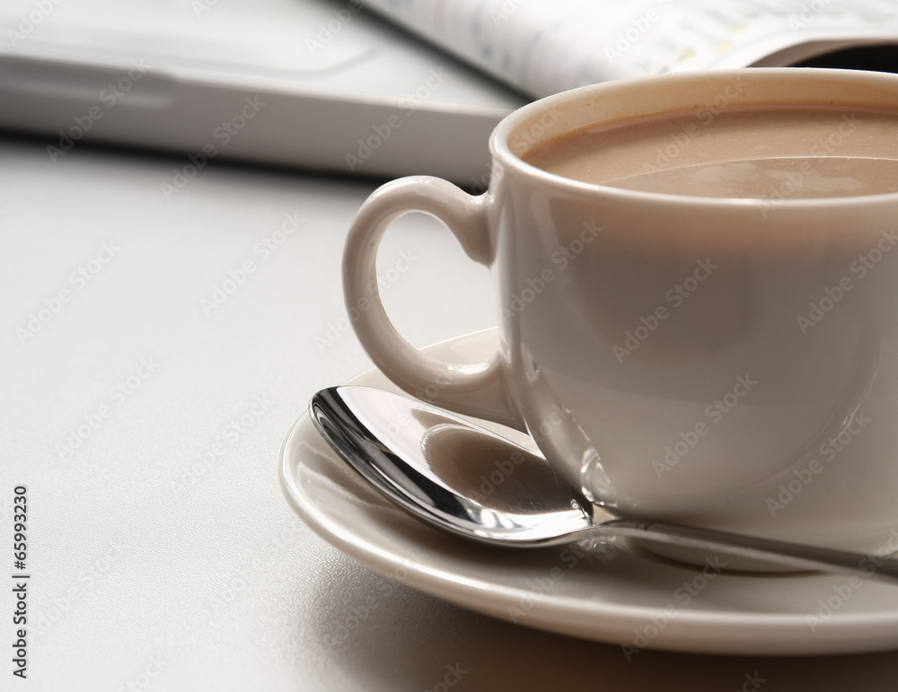 cup of coffee near the laptop and newspapers cup of coffee near the laptop and newspapers