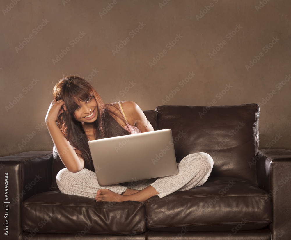 Young beautiful indian woman sitting on couch working on laptop Young beautiful indian woman sitting on couch working on laptop