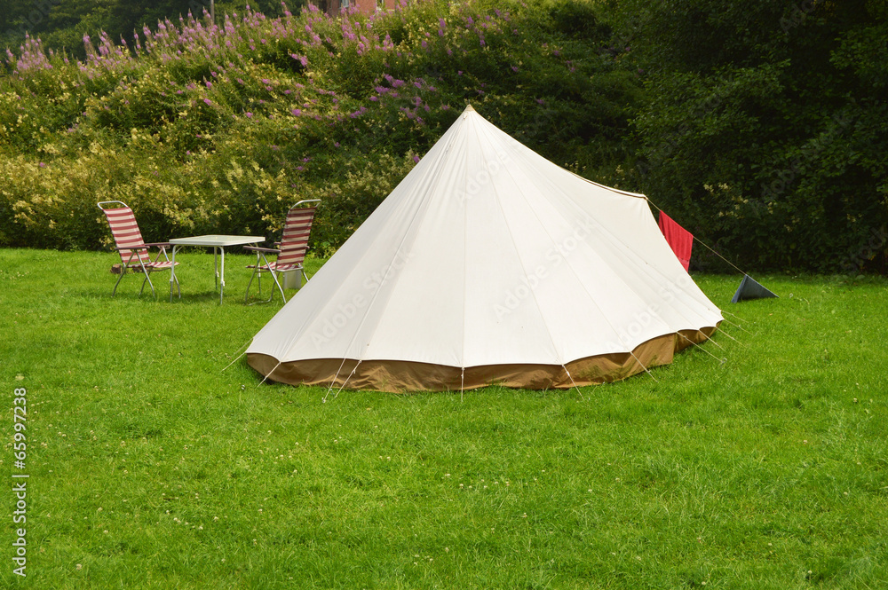 Campsite with a canvas tent and camp furniture on grass