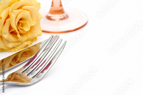 Place setting. Knife  fork and glass with yellow rose on white