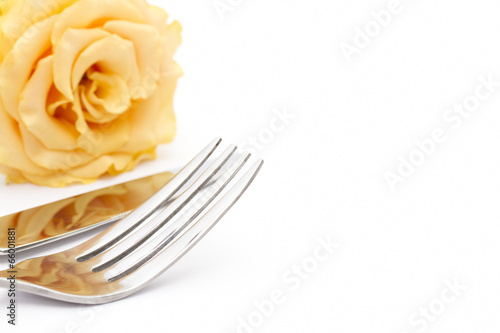 Place setting. Knife and fork with yellow rose on white
