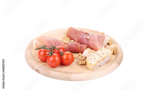 Prosciutto and tomatoes with bread on platter.