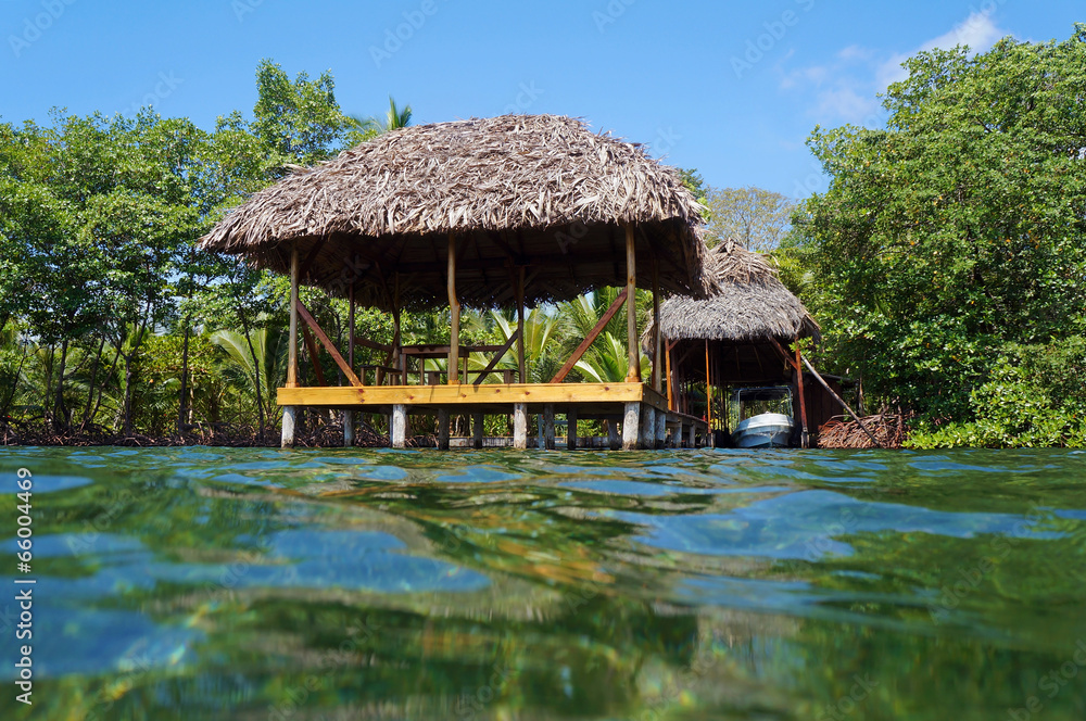 Tropical hut with thatch roof from water surface Tropical hut with thatch roof from water surface