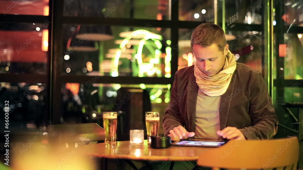 Young man watching photos on tablet computer and drinking beer Young man watching photos on tablet computer and drinking beer