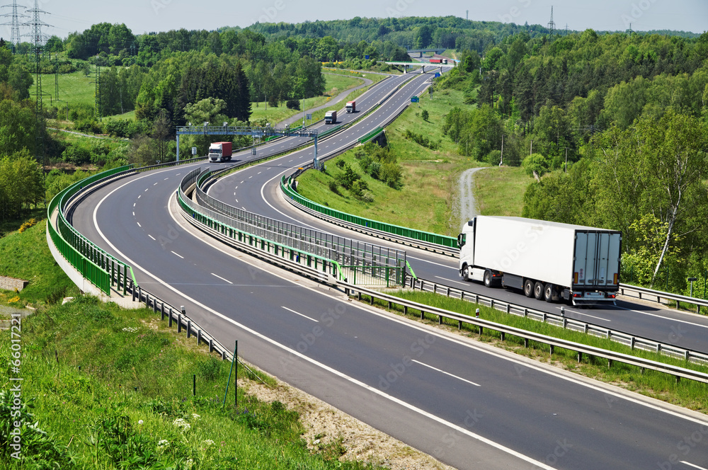 The highway between woods, moving trucks, electronic toll gates
