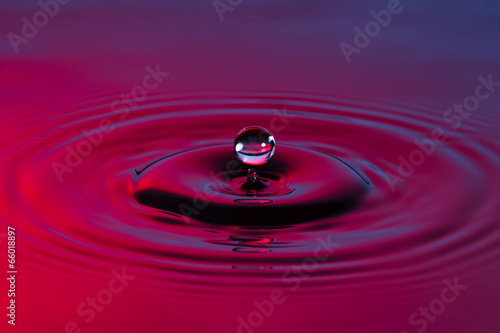 Water drop close up with concentric ripples colourful blue and r