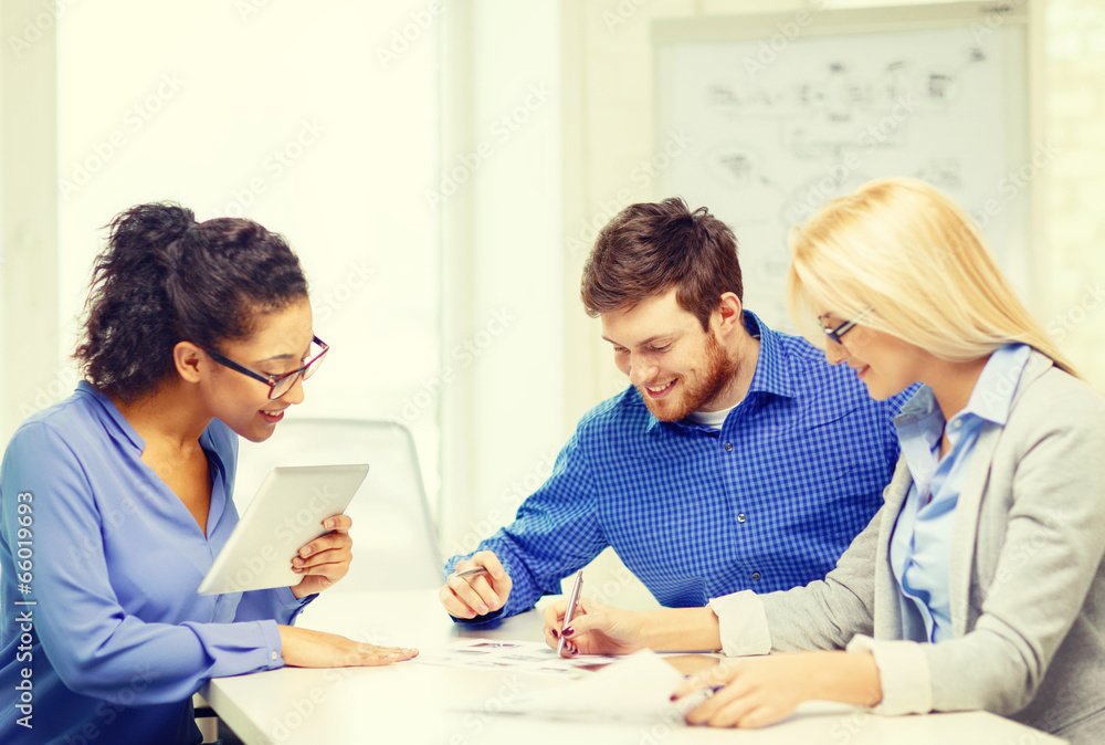 smiling team with table pc and papers working smiling team with table pc and papers working