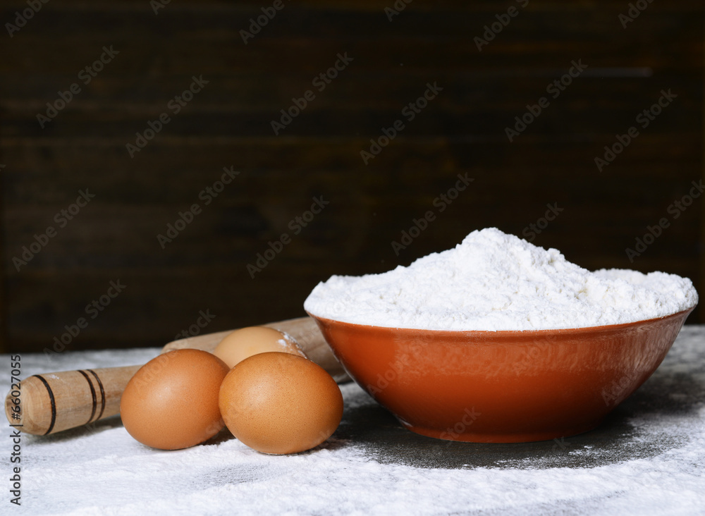Flour in bowl on table on wooden background Flour in bowl on table on wooden background