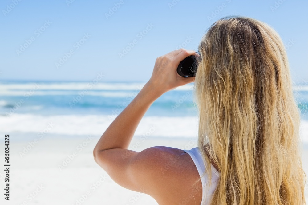 Blonde looking to the ocean through binoculars Blonde looking to the ocean through binoculars