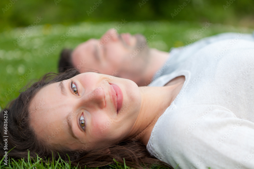 Attractive couple lying in grass at the park Attractive couple lying in grass at the park