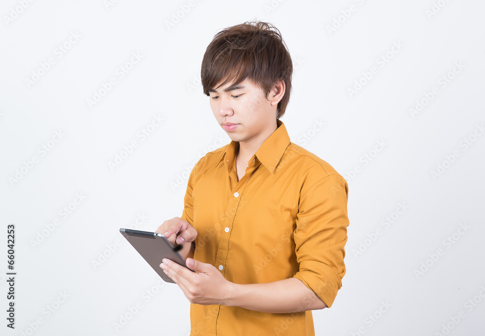 Handsome man in orange shirt playing tablet Handsome man in orange shirt playing tablet