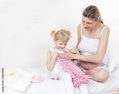 little girl and her pregnant mother with clothes for a baby