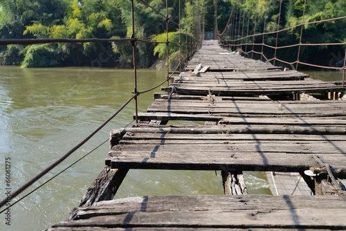 very old hanging footbridge across river.