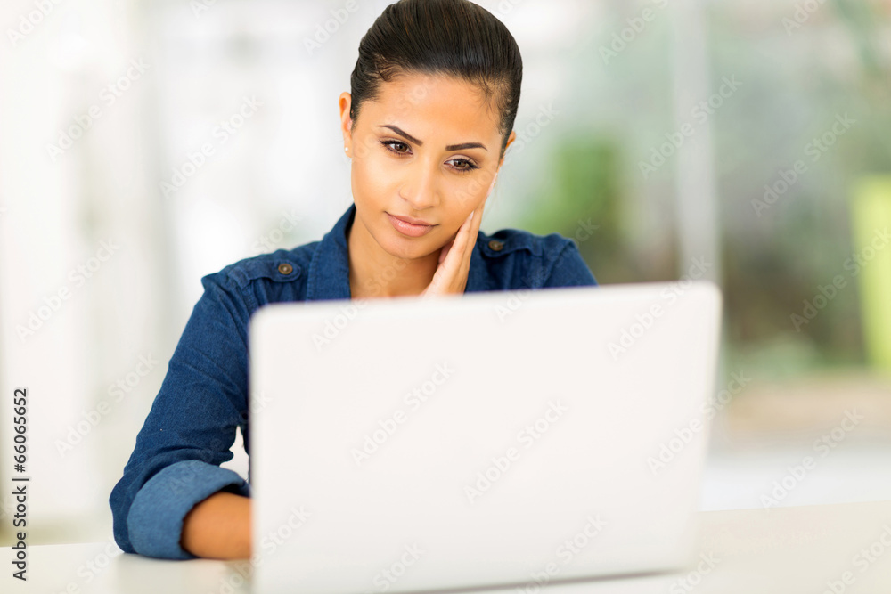 thoughtful young woman looking at the laptop screen thoughtful young woman looking at the laptop screen