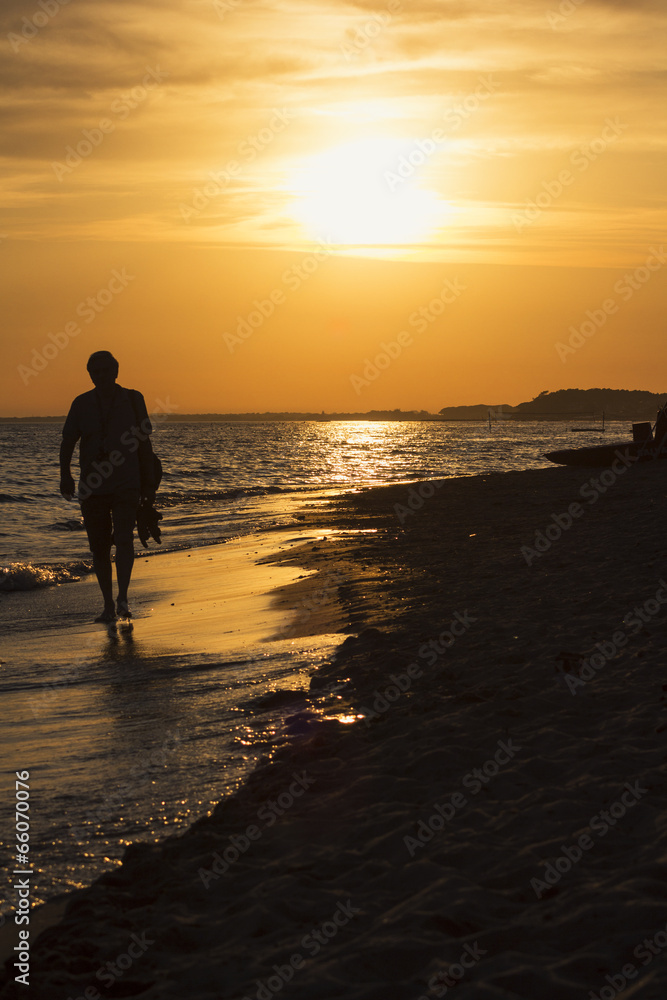 Uomo che cammina su spiaggia al tramonto Stock Photo | Adobe Stock