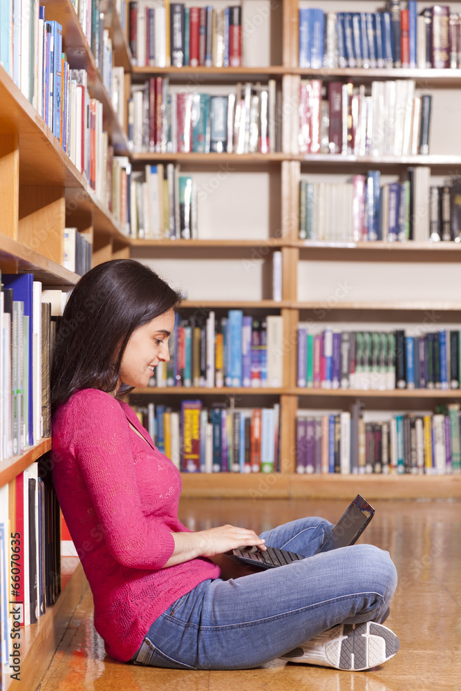 Happy smiling female student working with laptop in library Happy smiling female student working with laptop in library