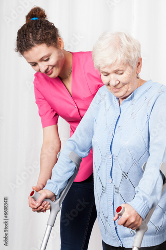 Nurse helps to walk the old woman