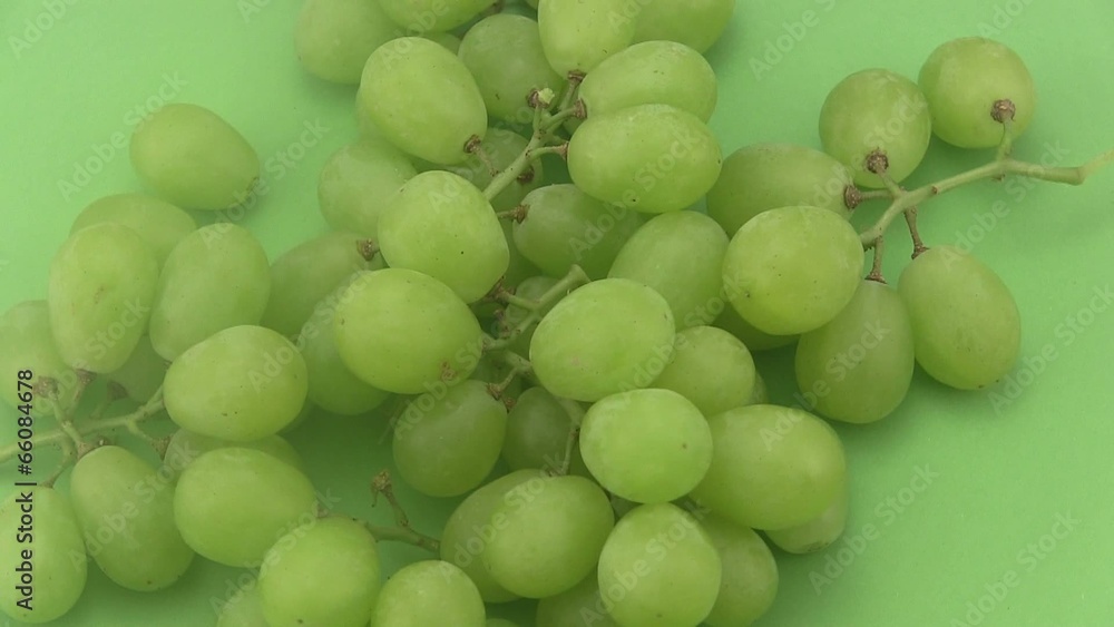 Ripe green grapes rotating a green background. Ripe green grapes rotating a green background.
