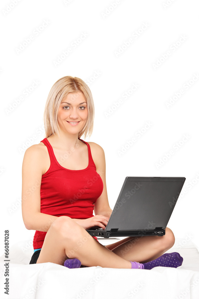 Blond woman working on a laptop seated on towel Blond woman working on a laptop seated on towel