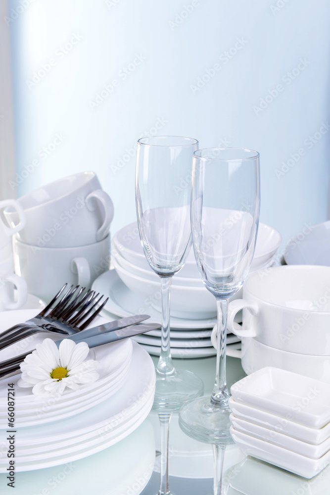 Set of white dishes on table on light background Set of white dishes on table on light background