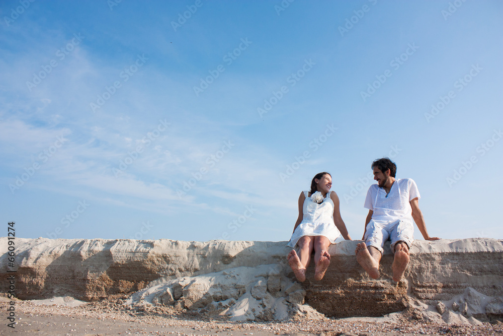 young couple sitting on the beach and laughing