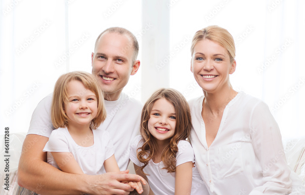 smiling parents and two little girls at home