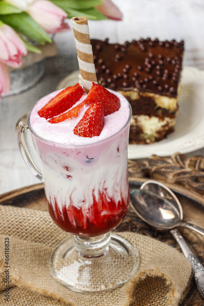 Strawberry milkshake and piece of cake in the background