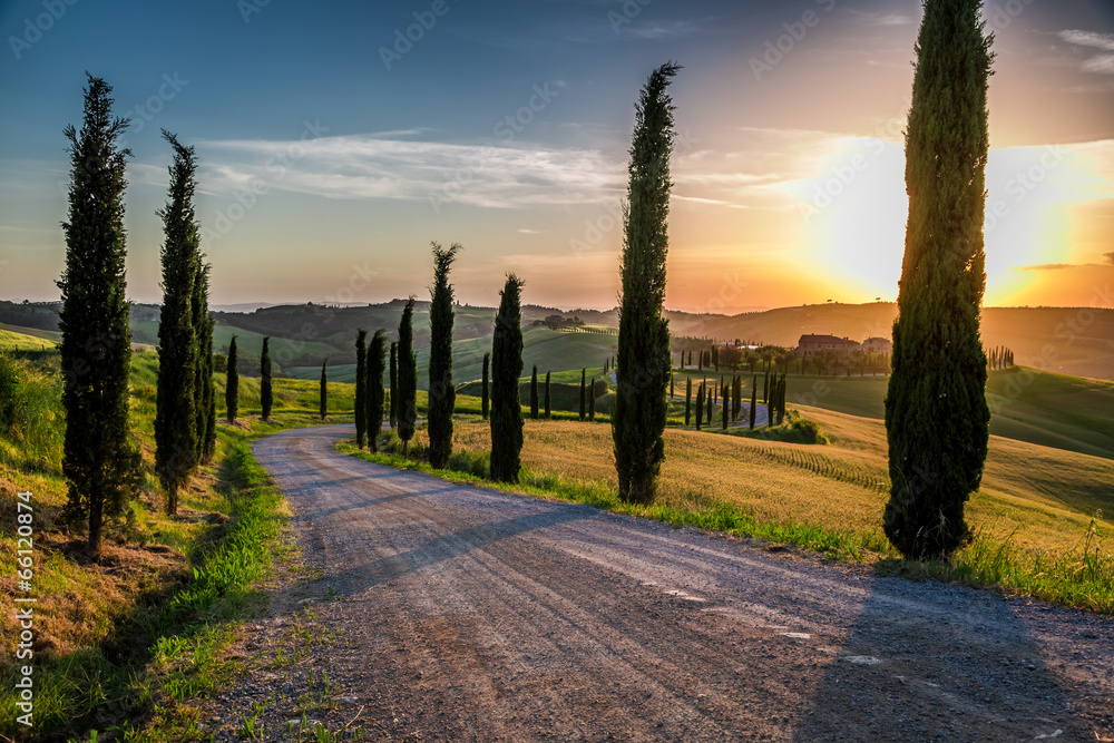 Sunset and winding road with cypresses in Tuscany