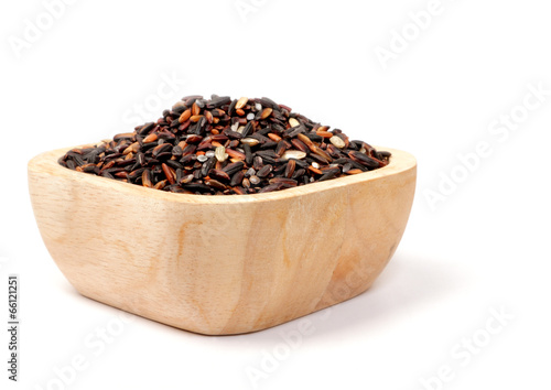 Uncooked thai black rice in a wooden bowls on white
