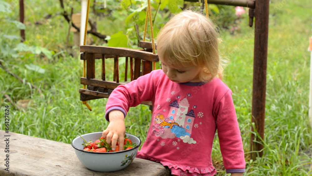 Cute Little Girl Eating Strawberry in Green Garden Cute Little Girl Eating Strawberry in Green Garden