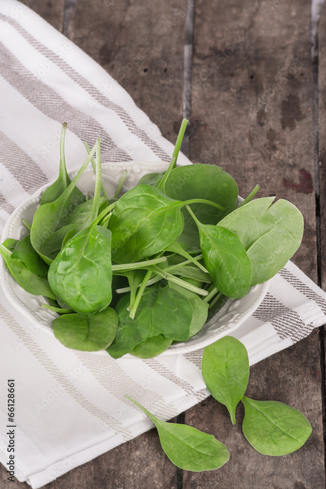 Fresh spinach in a bowl on wooden background Fresh spinach in a bowl on wooden background