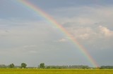 Rainbow with cloudy sky after rain over field